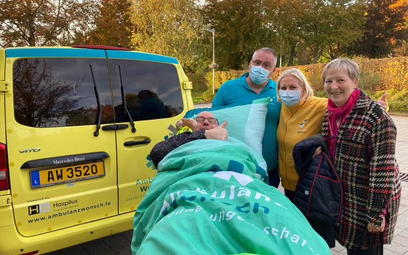 male patient on stretcher with wife and caretakers of ambulanzwonsch in front of ambulance in stromberg germany